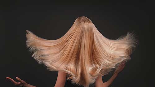 Modell mit langen Haaren mit Strähnen in Nuacen von Blond bis Hellbraun